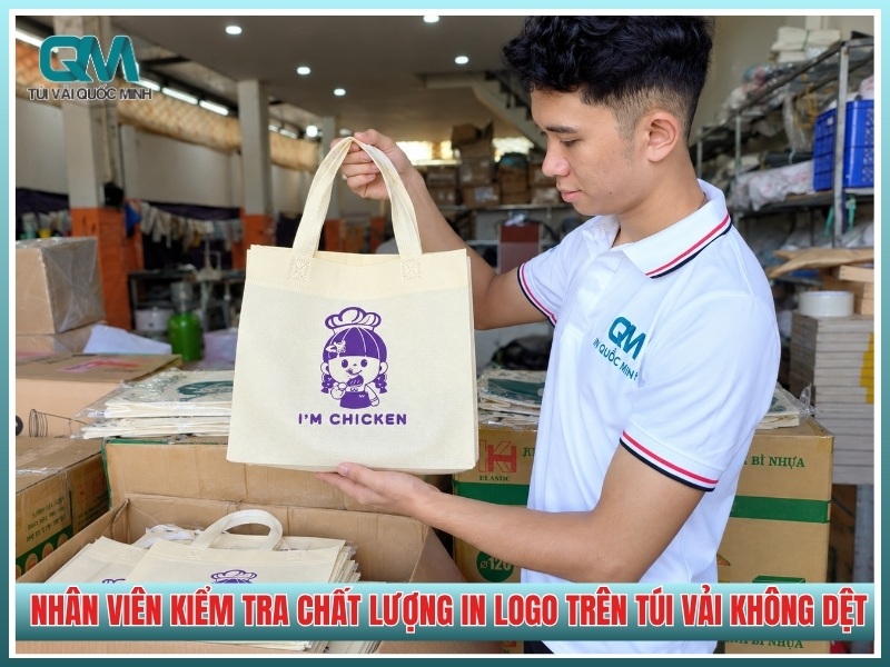 nhân viên kiểm tra chất lượng in logo trên túi vải không dệt tại xưởng