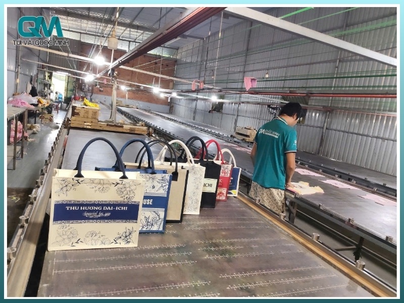 nhân viên xưởng In Túi Vải Quốc Minh đang kiểm tra chất lượng in logo trên túi đay